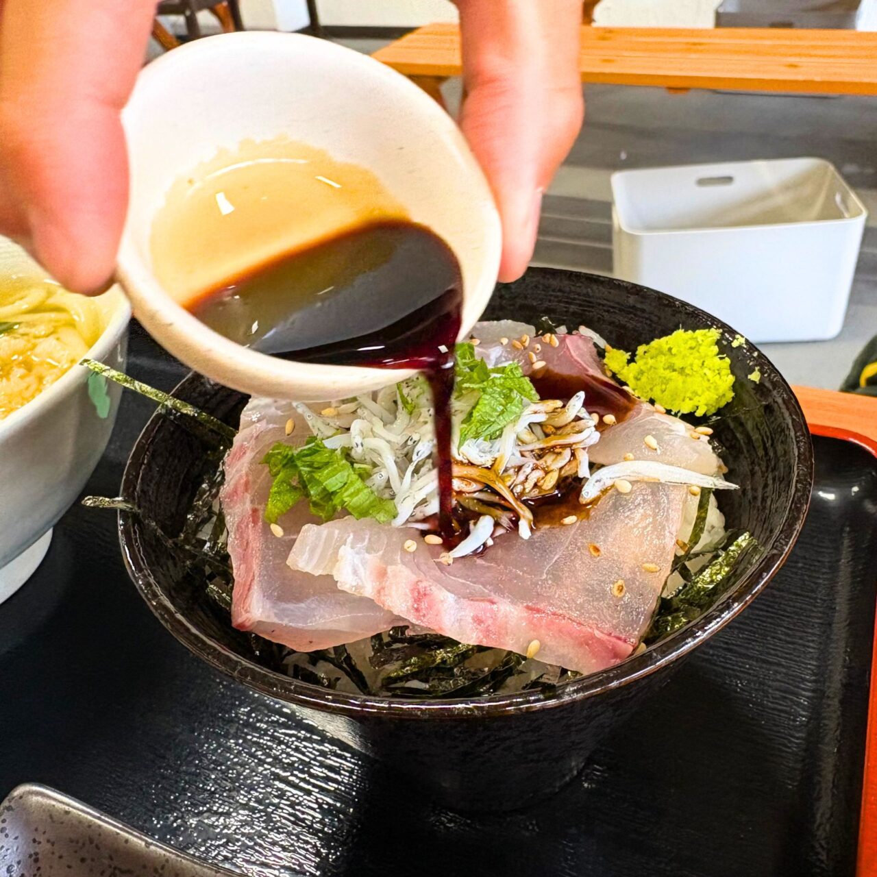 鯛の刺身丼に醤油をかける様子