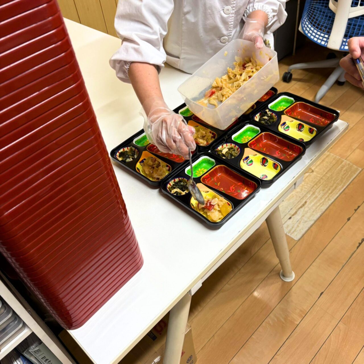 一人ひとりのメニューに合わせて手作業でお弁当を詰めている様子